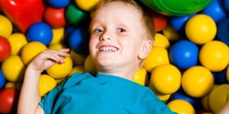 A young boy lays on top of a ball pit